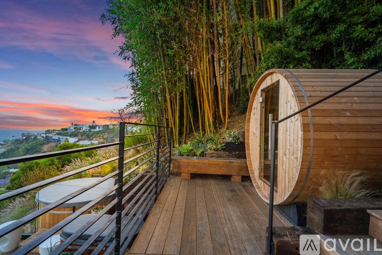 A wooden deck with a railing and a round window overlooking a bamboo forest.