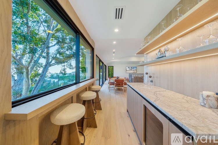 A modern kitchen with a bar area and a view of trees outside the window.