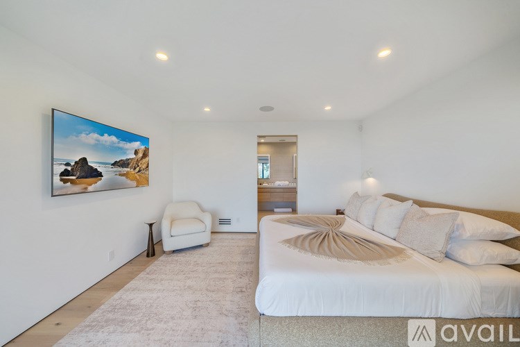A bedroom with a large bed and a painting on the wall.