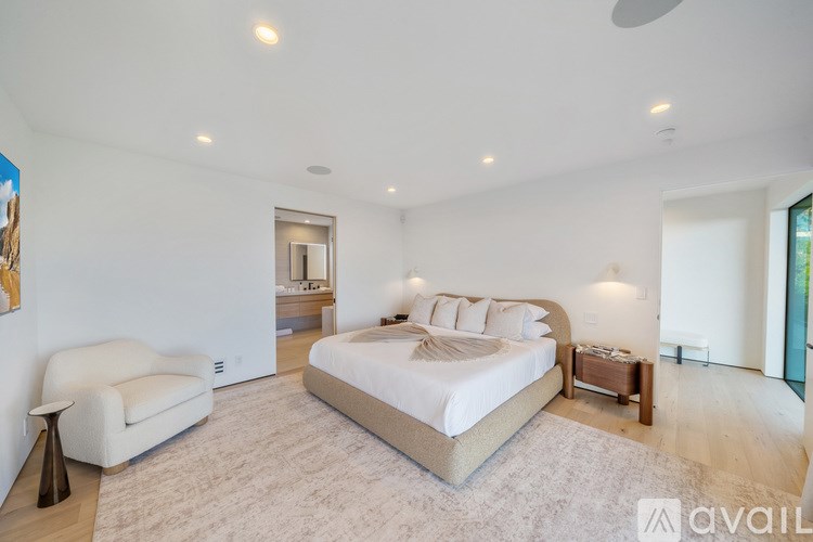A bedroom with a large bed, a chair, and a painting on the wall.