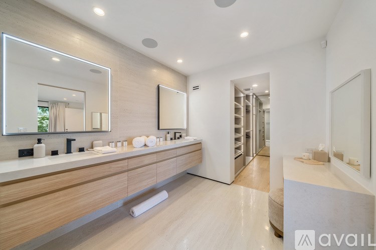 A bathroom with a large mirror and a wooden vanity.