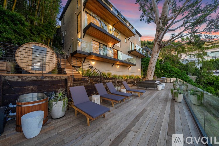 A wooden deck with lounge chairs and a hot tub is available for rent.