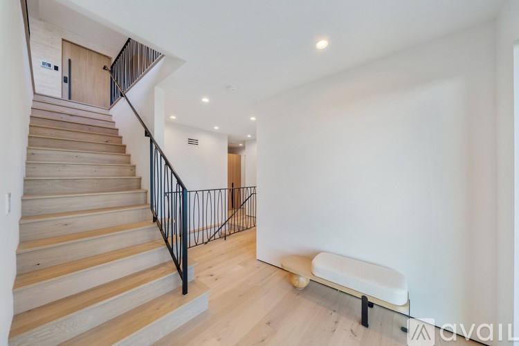 A staircase with wooden steps and a black railing leads to a second floor.