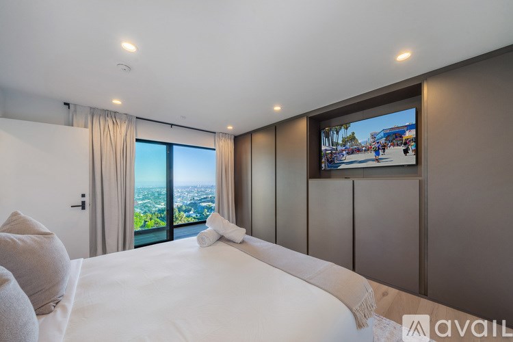 A bedroom with a large bed and a television displaying a cityscape.