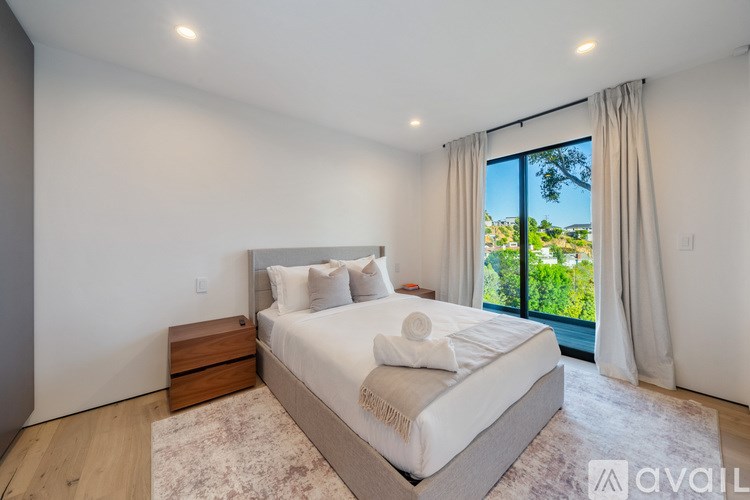 A bedroom with a large bed, a window with a view, and a rug on the floor.