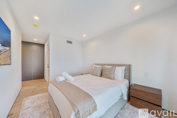 A bedroom with a large bed and a wooden nightstand.