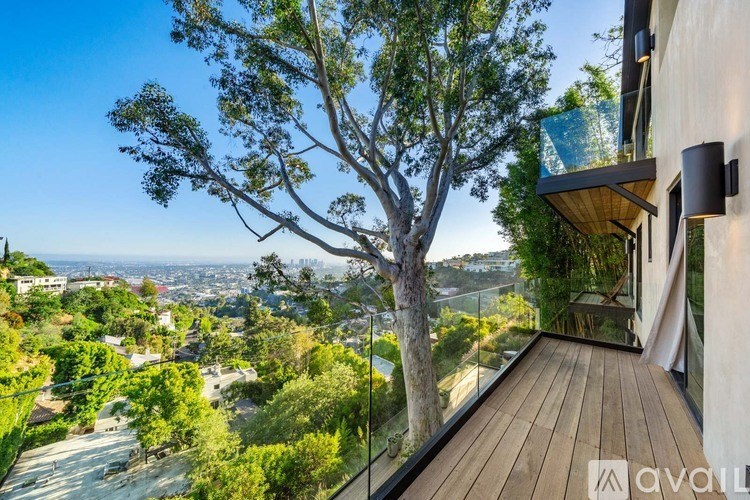 A balcony with a view of a cityscape and a large tree.