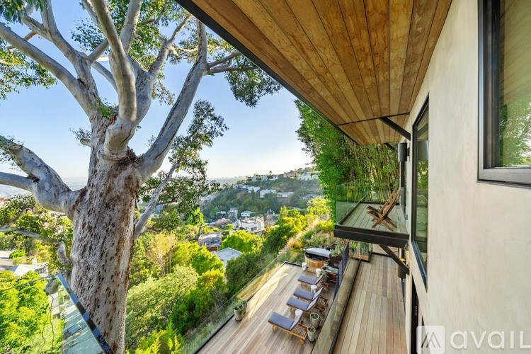 A balcony with a table and chairs overlooks a tree and buildings.