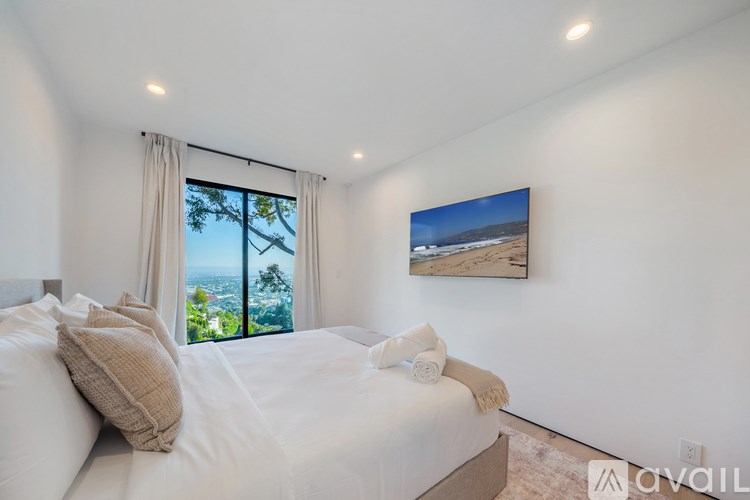 A bedroom with a large bed and a painting of a beach scene on the wall.