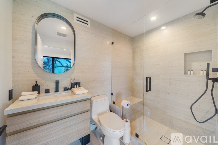 A bathroom with a toilet, sink, mirror, and shower.
