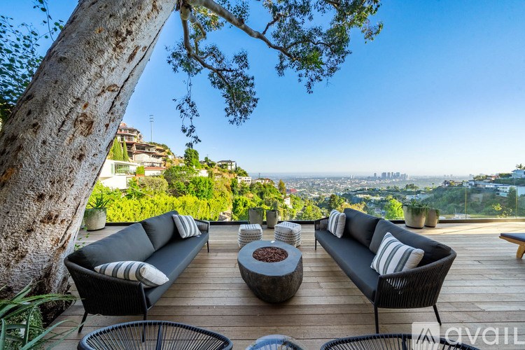 A patio with a black sofa and a coffee table with a view of the city.
