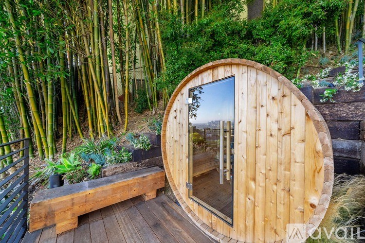 A round wooden structure with a glass door in the middle of a forest.