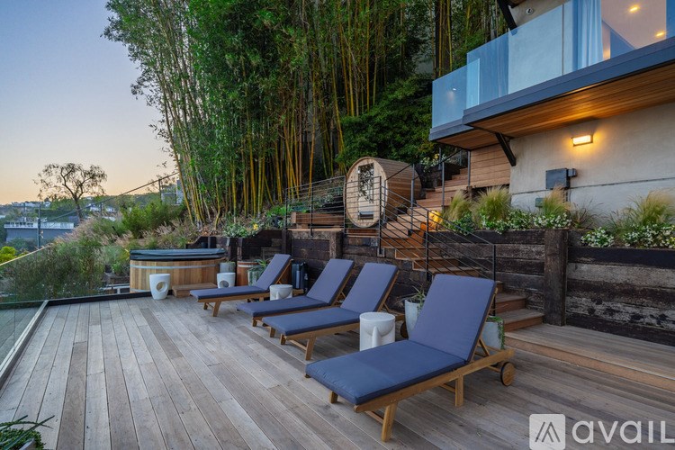 A wooden deck with chairs and a hot tub surrounded by trees.