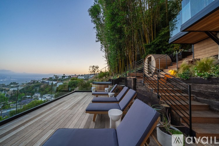A wooden deck with benches and a railing overlooking a cityscape at dusk.