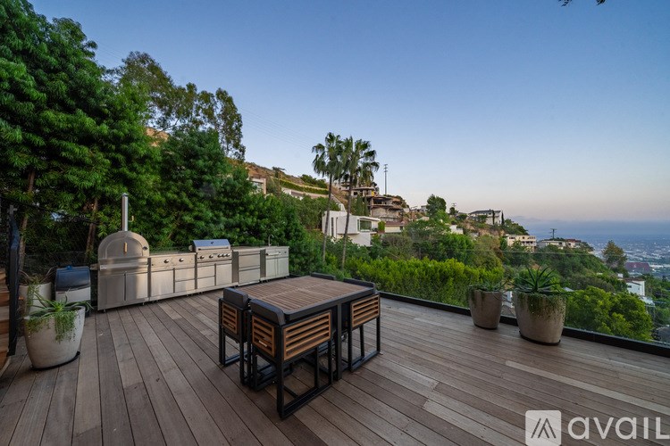 A wooden deck with a table and chairs overlooks a cityscape.