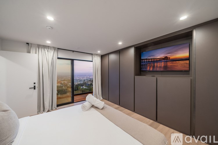 A modern bedroom with a large bed and a television on the wall.
