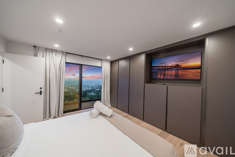 A modern bedroom with a large bed and a television on the wall.
