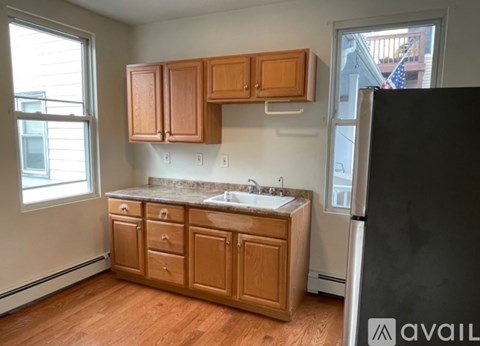 A kitchen with wooden cabinets and a black refrigerator.