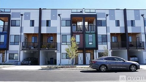 A modern apartment building with a car parked in front.