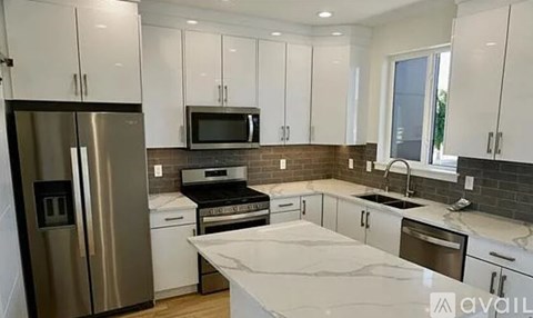 A kitchen with white cabinets and a marble countertop.