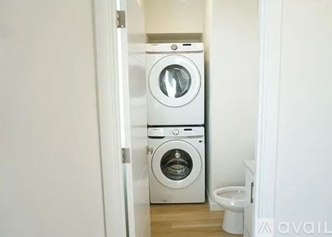 A white washing machine and dryer stacked on top of each other in a small room.
