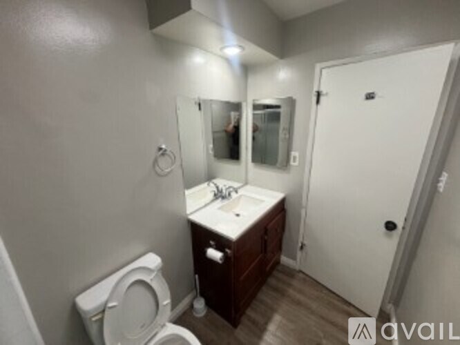A bathroom with a toilet, sink, mirror, and a door.