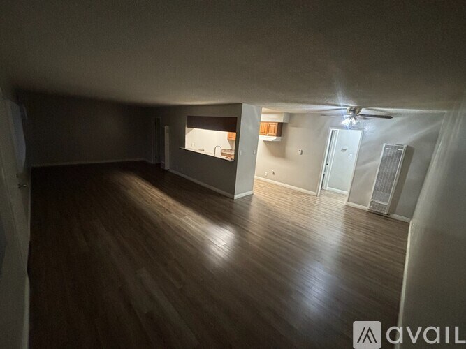 A spacious room with wooden flooring and a ceiling fan.