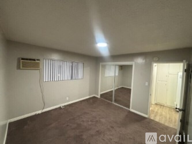 A room with a carpeted floor and a window with blinds.