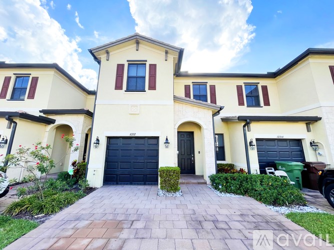 A two-story house with a black garage door and a brick driveway.