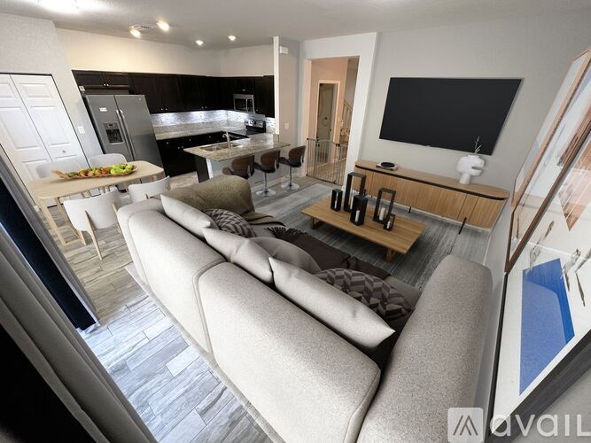 A modern living room with a grey sofa and a kitchen in the background.