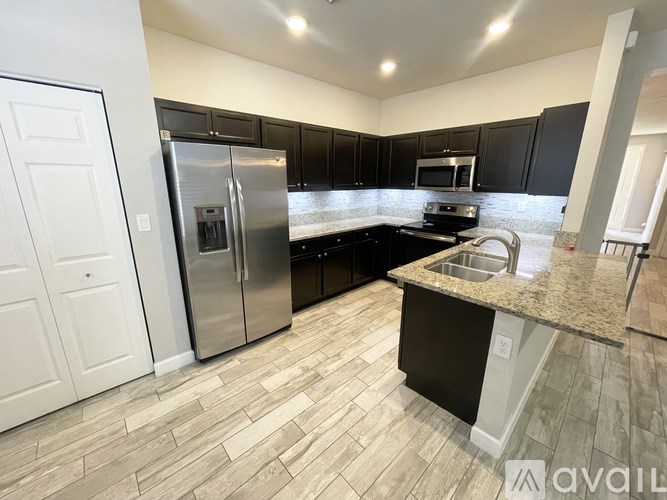 A kitchen with black cabinets and a granite countertop.