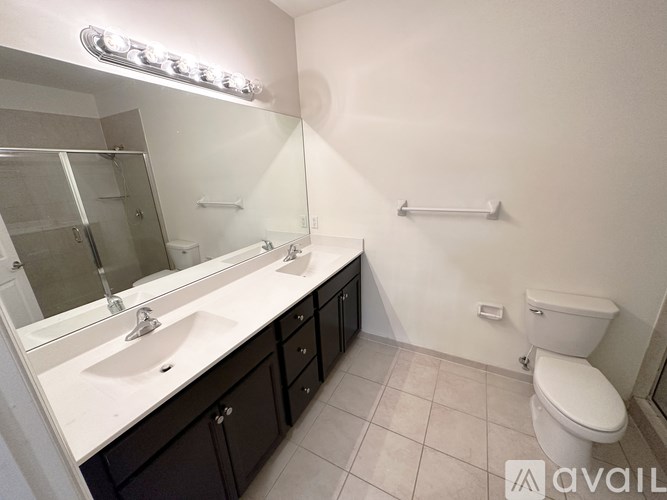 A bathroom with a sink, mirror, toilet and a towel bar.