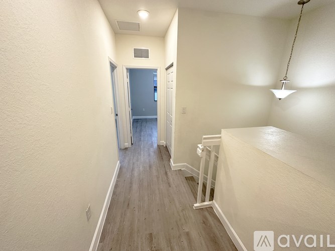 A long hallway with a door at the end and a light hanging from the ceiling.