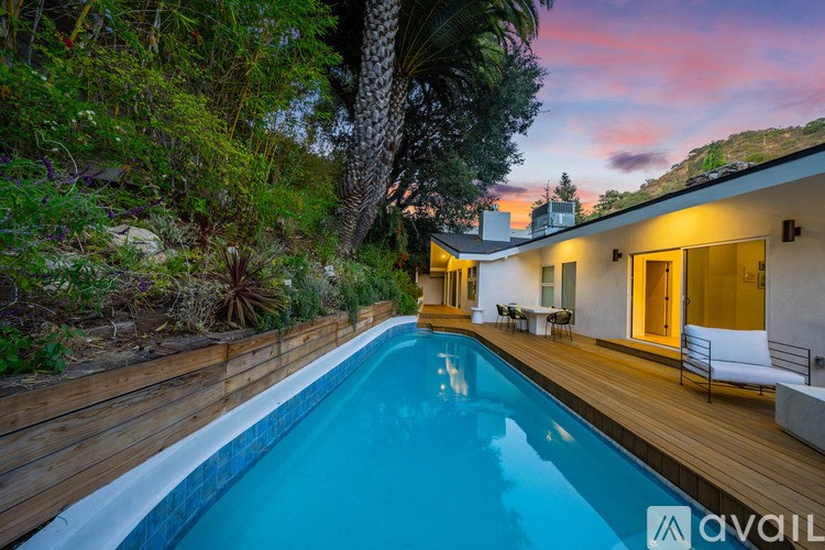 A pool in a backyard with a house and trees in the background.