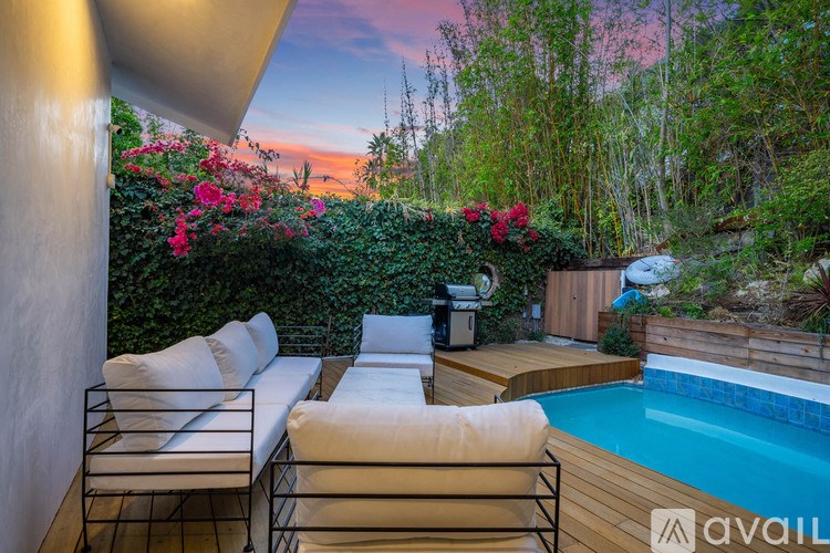 A poolside lounge area with white cushioned chairs and a wooden deck.