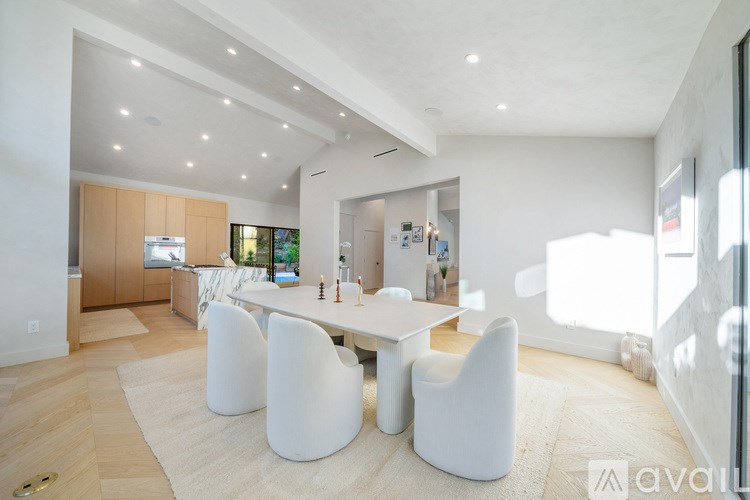 A modern dining room with a white table and chairs.