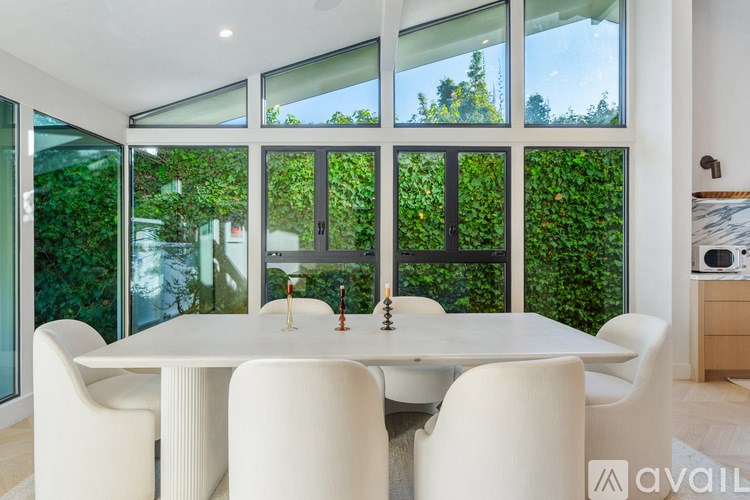 A dining room with a table surrounded by white chairs.