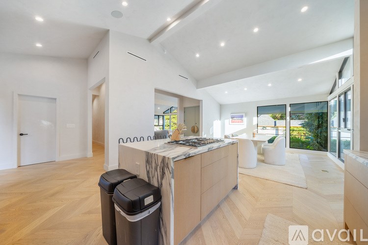 A modern kitchen with a marble countertop and wooden flooring.
