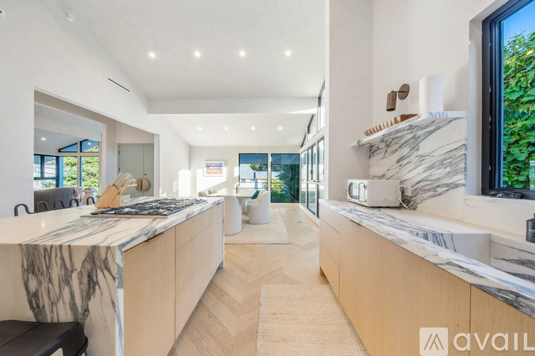 A modern kitchen with marble countertops and wooden cabinets.