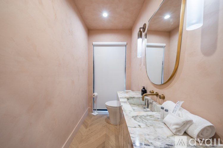 A bathroom with a marble countertop and a round mirror.