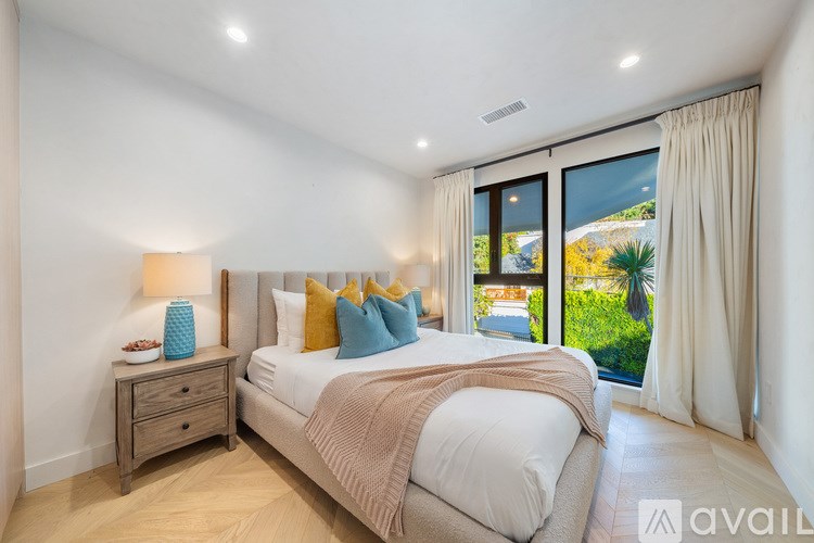 A bedroom with a large bed and a view of the outdoors through the window.