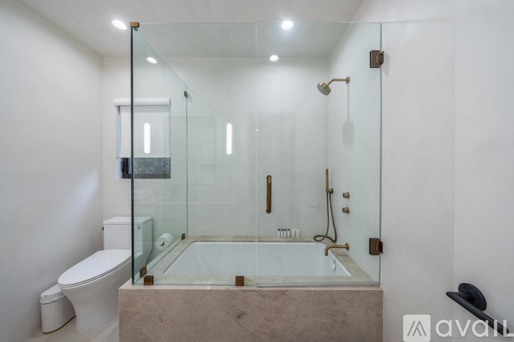 A bathroom with a glass shower stall and a toilet.