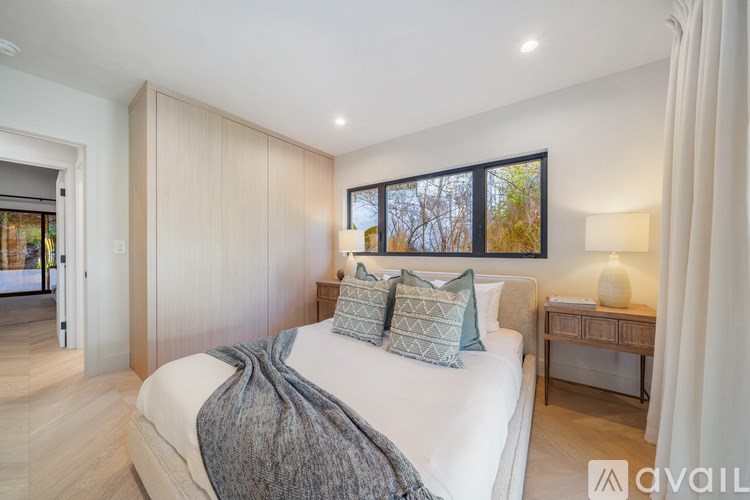 A bedroom with a large bed and a window with a view of trees.
