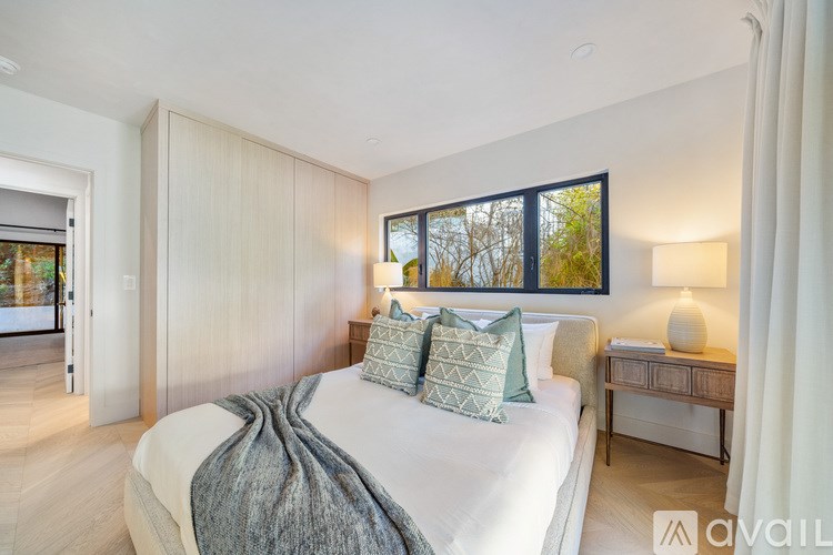 A bedroom with a large bed and a window with a view of trees.