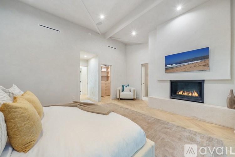A bedroom with a fireplace and a painting of a beach scene on the wall.