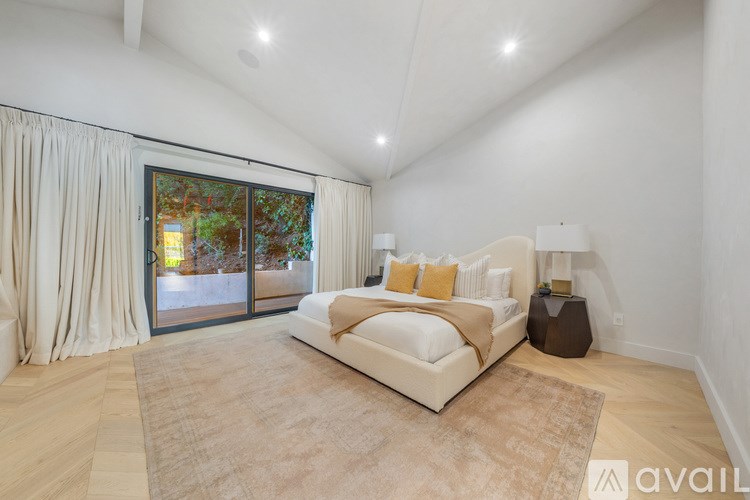 A bedroom with a large bed and a sliding glass door leading to a garden.