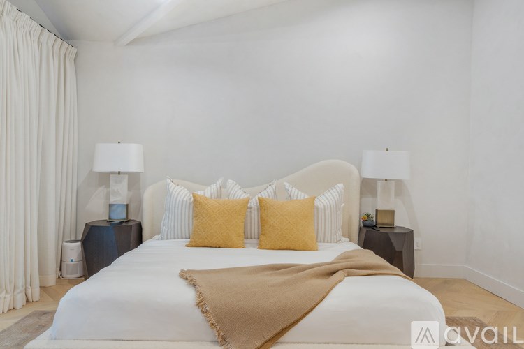 A bedroom with a white bed and a white wall.