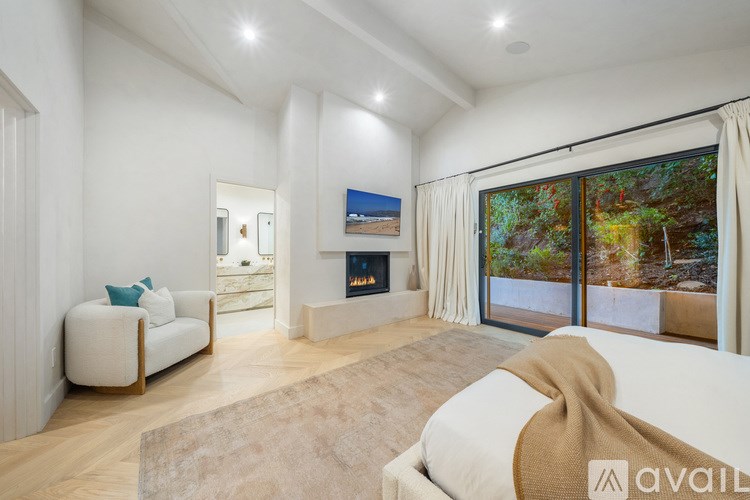A living room with a couch, a fireplace, and a large window with a view of trees.