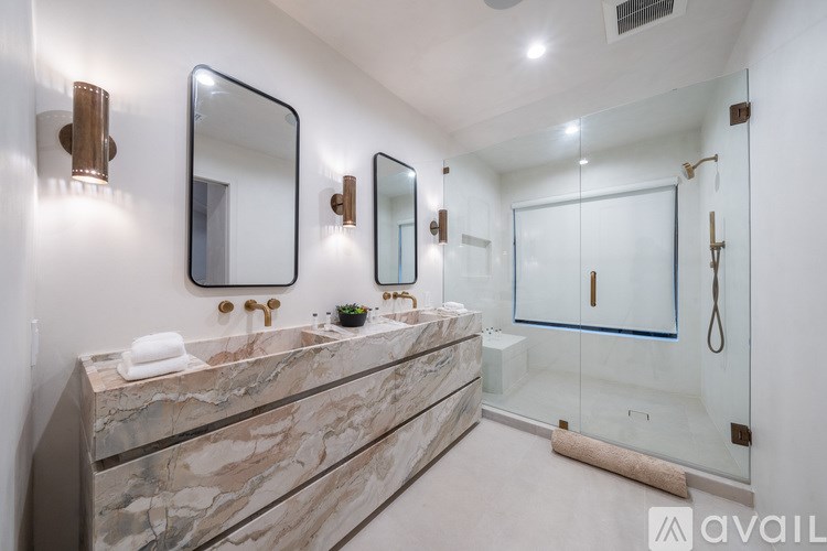 A bathroom with a marble countertop and a glass shower door.