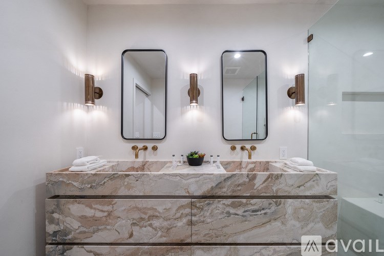 A bathroom with a marble countertop and two round mirrors.